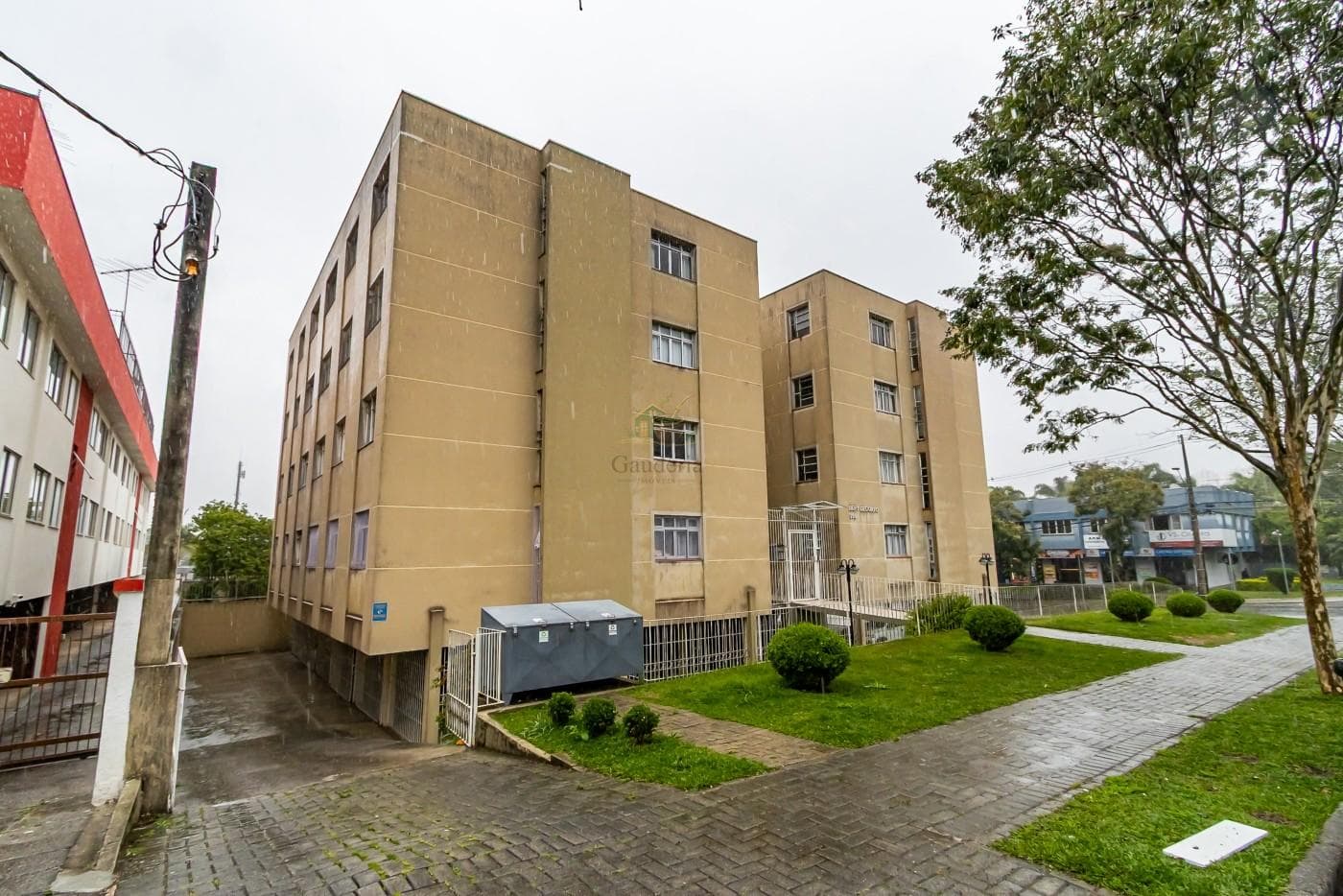 Fachada do edifício residencial de múltiplos andares com pintura em tom bege e gramado.